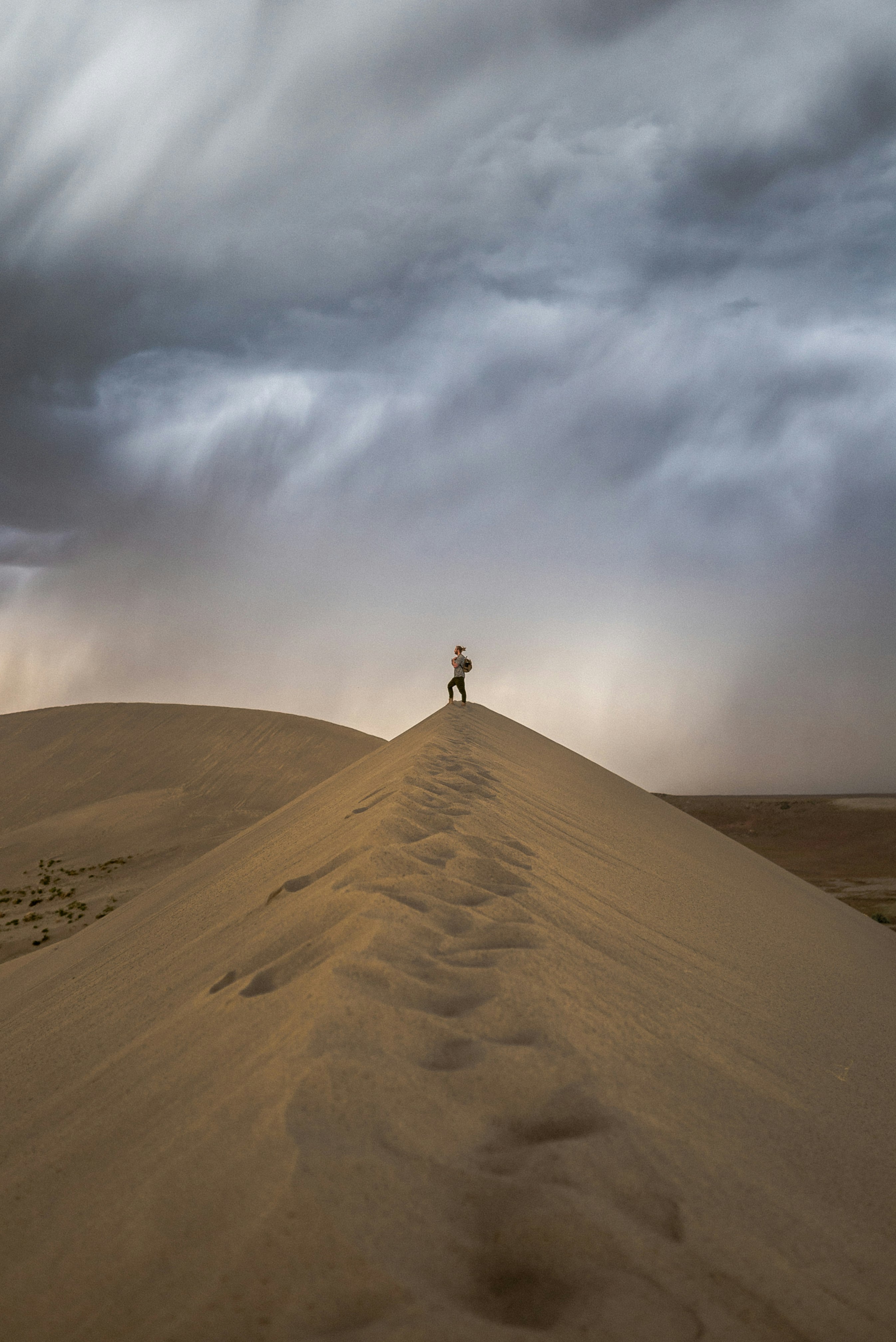 person standing on brown sand under white clouds during daytime